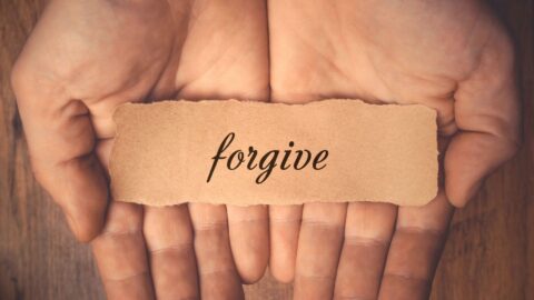 Hands holding the word "forgive"
