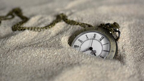 Watch in sand representing slave to time
