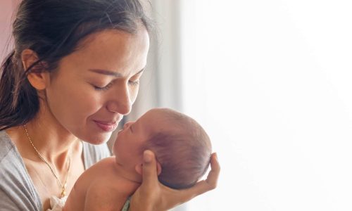 Woman holding her newborn demonstrating the power of God's love for us