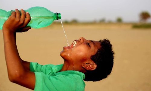 boy in desert drinking water