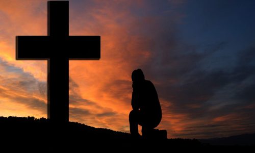 man praying before cross