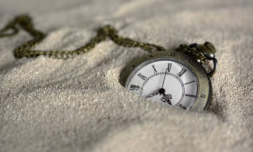 Watch in sand representing slave to time